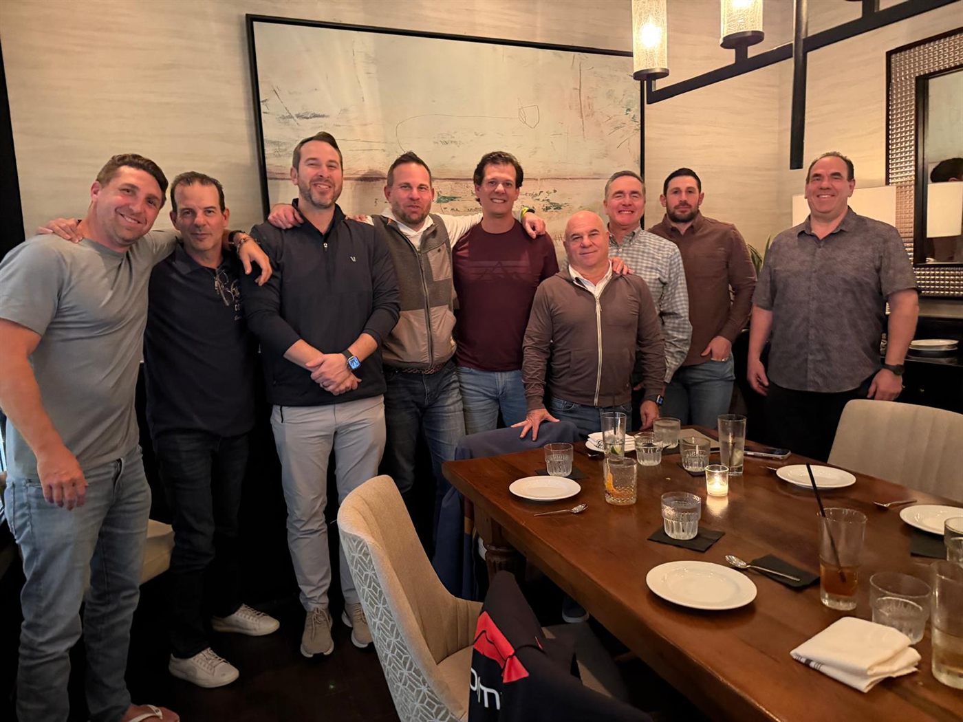 Nine members standing shoulder to shoulder behind a long restaurant table.